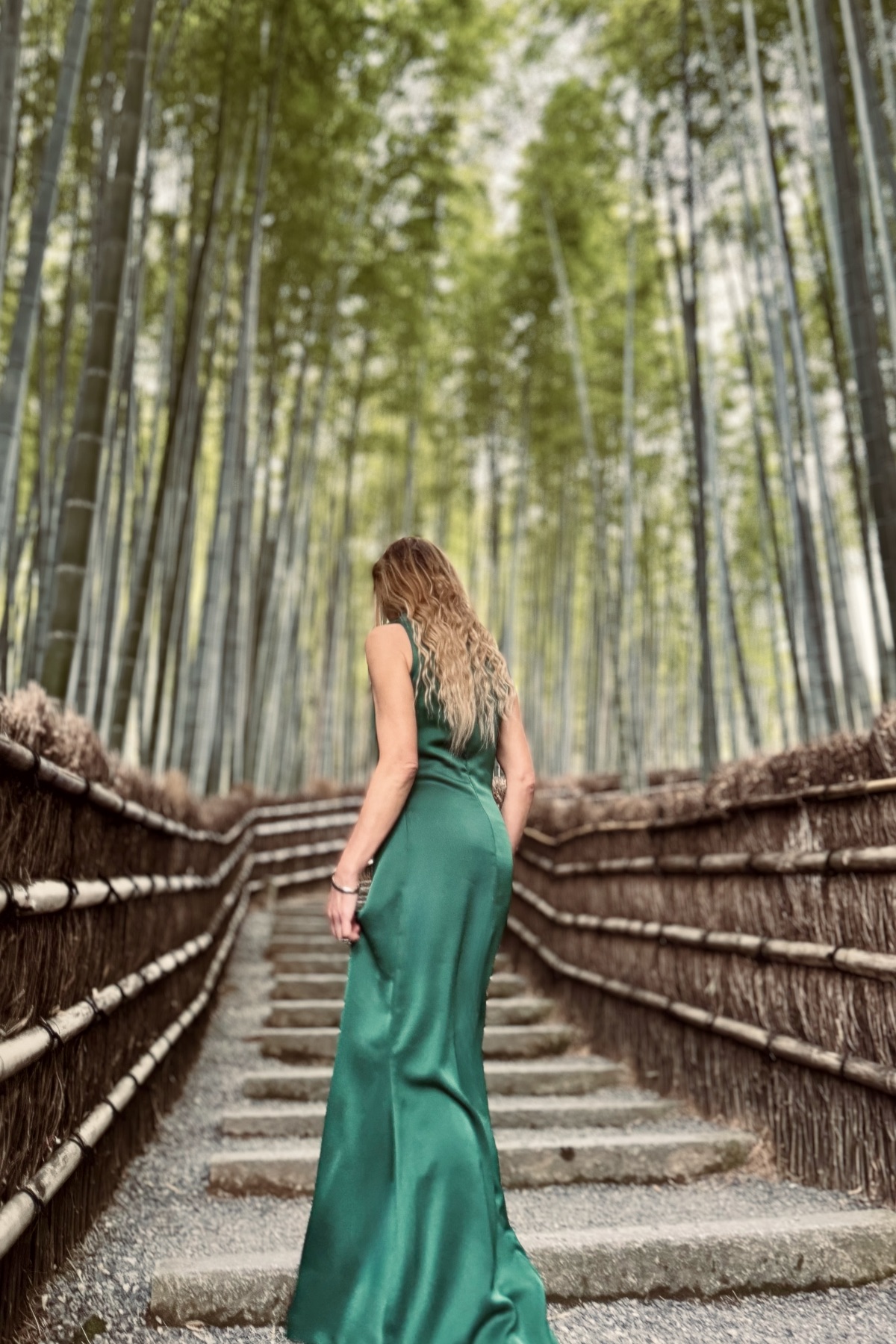 Muse in an emerald dress walking a bamboo forest path